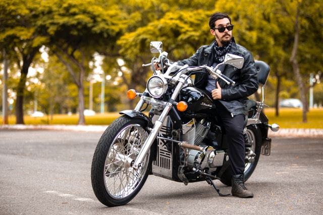 Motorkár, muž v koženej bunde sedí na motorke, namyslený.jpg